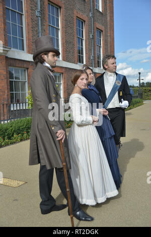 Queen Victoria, 2 gentlemen and her Baroness Lehzen stand in front of Kensington Palace and look at the grounds. Stock Photo