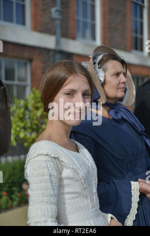 Queen Victoria, 2 gentlemen and her Baroness Lehzen stand in front of Kensington Palace and look at the grounds. Stock Photo