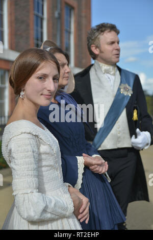 Queen Victoria, 2 gentlemen and her Baroness Lehzen stand in front of Kensington Palace and look at the grounds. Stock Photo