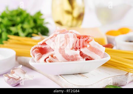 Bacon. Ingredients for cooking Carbonara pasta, spaghetti, egg, peppers, salt and hard parmesan cheese. Italian cuisine. Stock Photo