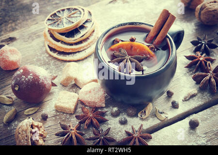 Mulled wine in black mug and ingredients on table. Retro toned. Stock Photo