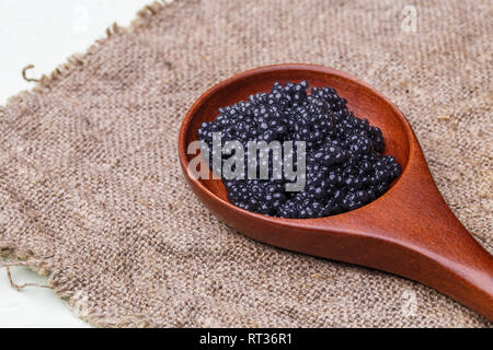 Wooden spoon with black caviar Stock Photo