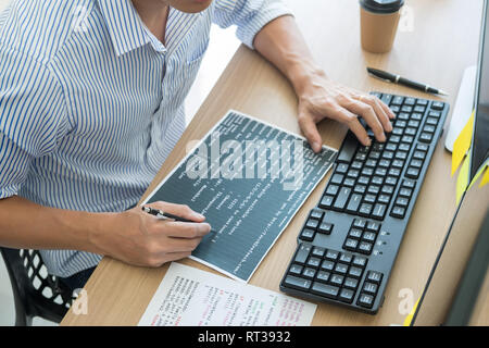 Serious busy hipster young web software developer programmer is coding or programming on a desktop computer information in modern office technologies  Stock Photo