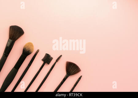 Various small brushes small for applying decorative makeup on a delicate pink background. Care and beauty concept. Stock Photo