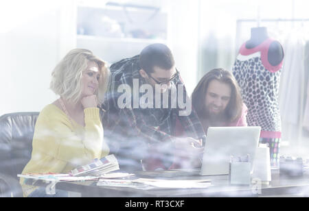 view from behind glass.group of designers working on new sketches Stock Photo
