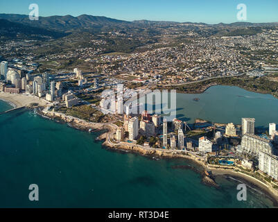 Drone point of view Calpe spit between Mediterranean Sea and lake. Cityscape modern skyscrapers sunny day green turquoise water Stock Photo