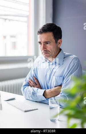 Serious businessman sitting at desk in office Stock Photo