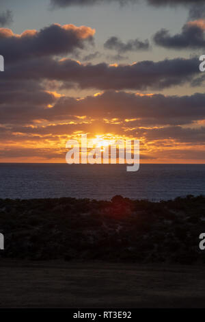 Sun shining through orange clouds during sunset at the coast of Geraldton, Western Australia Stock Photo