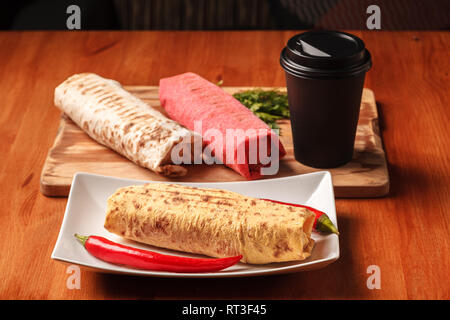 Traditional Middle Eastern snack and coffee. Shawarma sandwich gyro fresh roll of colorful lavash pita bread, chicken beef shawarma falafel Recipe Tin Stock Photo