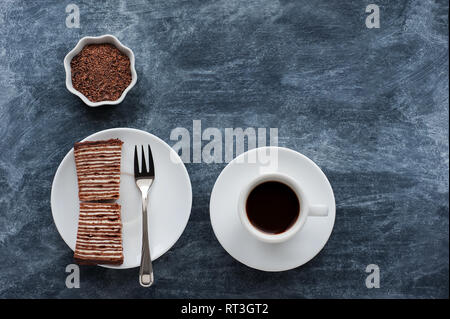 Creative layout made of chocolate crumbs , cup with coffee and sweet chocolate cake on grey background. Flat lay. Food concept. Stock Photo
