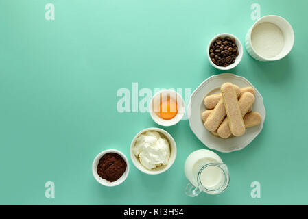 Ingredients for cooking tiramisu: sponge fingers cookies (Savoiardi, Ladyfinger, biscuit), mascarpone, cream, sugar, cocoa, coffee and egg on blue bac Stock Photo