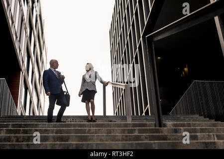 Senior businessman and businesswoman talking on stairs in the city Stock Photo