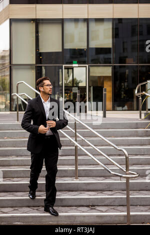 Businessman with earbuds walking on stairs in the city Stock Photo