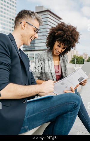 Two happy colleagues working together outside office building Stock Photo