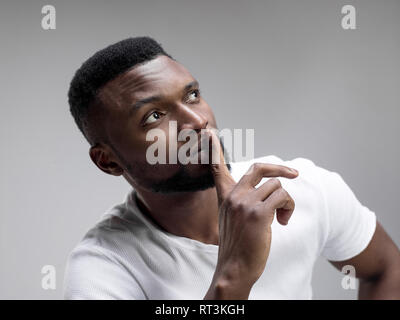 Serious african male keeps fore finger on lips, tries to keep conspiracy, says: Shh, make silence please. Isolated shot of man shows silence gesture Stock Photo