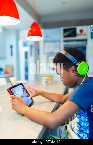 Boy with headphones and digital tablet playing video game Stock Photo