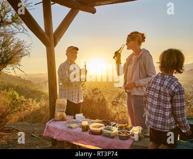 Chile, Santiago, mother with grandfather and son having a picnic in the mountains at sunset Stock Photo