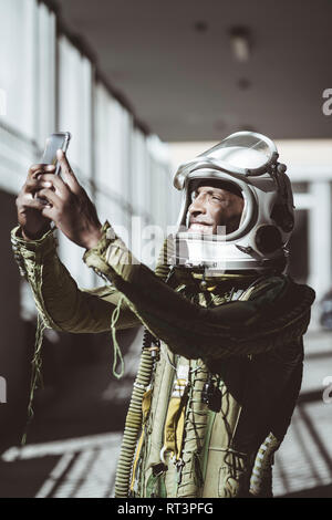 Happy astronaut in spacesuit using smartphone Stock Photo