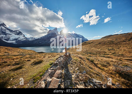 Chile, Torres del Paine National park, woman standing on rock in front of Torres del Paine massif at sunrise