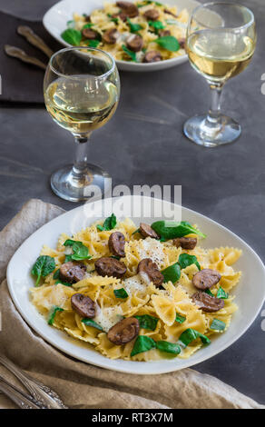 Fresh homemade farfalle pasta with mushrooms and spinach on concrete background. Stock Photo