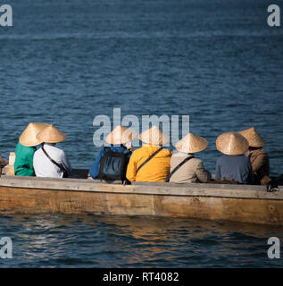 Tourists wearing tradtional hats in a boat in Miyajima, Japan Stock Photo