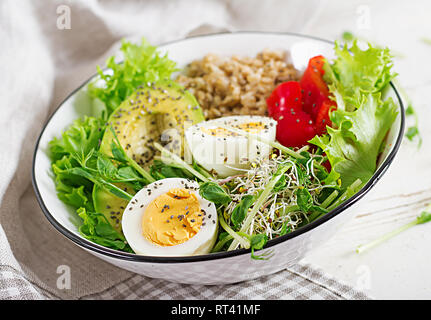 Fresh salad. Breakfast bowl with oatmeal, paprika, avocado, lettuce, microgreens and boiled egg. Healthy food. Vegetarian buddha bowl. Stock Photo
