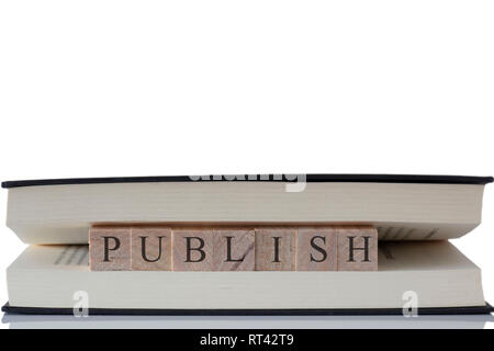 Publish written on wooden blocks inside a book isolated on a white background with reflection Stock Photo