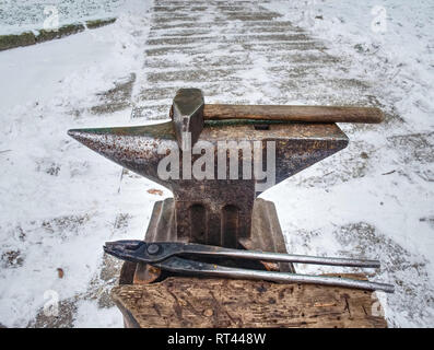 Used hammer and anvil ready for outside horse shoeing. Cold winter day in front of horse barn. Detail of old tool Stock Photo