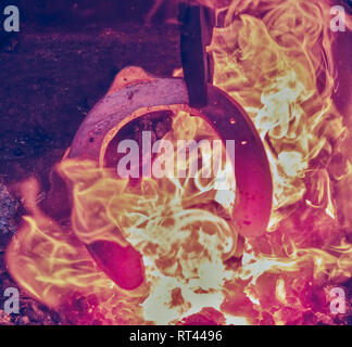 Iron bar heating in old fashioned blacksmith furnace with burning coals Stock Photo