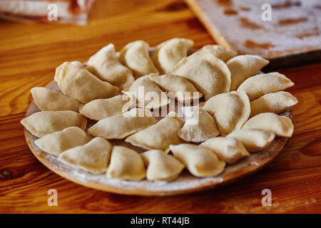 Dumplings raw on a wood board. The process of cooking Stock Photo