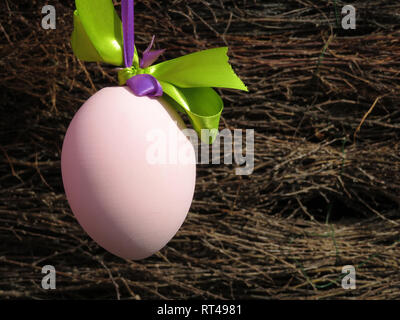 Easter egg with festive ribbon on wicker fence background. Easter decorations on the street, spring background Stock Photo