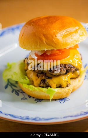 Smashed hamburger on a plate with melted cheese Stock Photo
