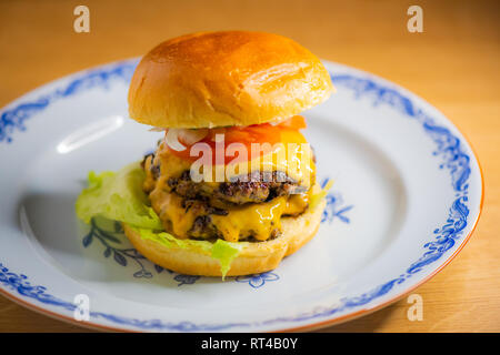 Smashed hamburger on a plate with melted cheese Stock Photo