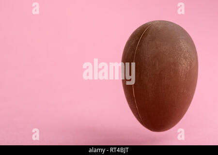 big chocolate Easter egg on pink background with copy space funny creative concept Stock Photo
