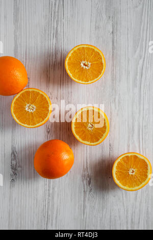 Halved and whole oranges on white wooden table, top view. Overhead, from above, flat lay. Stock Photo