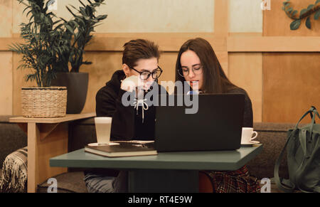 Pretty female students cooperating for completing common project learning in cafe interior with laptop computer Stock Photo