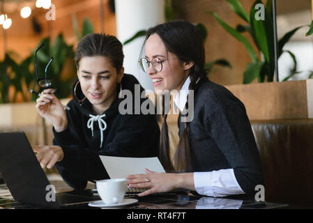 Cheerful female students having positive conversation cooperating on doing homework together Stock Photo