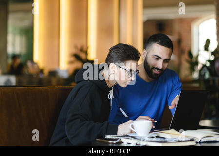 Male and female students watching training webinar and making notes with information for common project Stock Photo