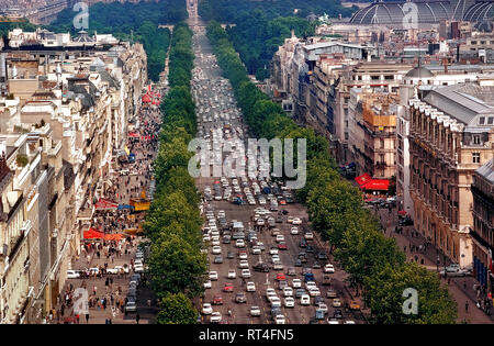 An aerial view shows the beautiful tree-lined Champs-Élysées, one of the busiest and most congested avenues in all of Paris, France. The famous 1.2 mile-long (1.9 km) thoroughfare runs between two of the French capital's monumental landmarks, the Place de la Concorde and Arc de Triomphe. Since this photograph was taken in 1983, the 11 lanes of traffic have been reduced to eight and there are plans to reduce vehicle use even more in order widen the sidewalks and make the street more pedestrian friendly by the mid-2020s. Stock Photo