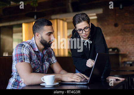 Two clever students having discussion something in the laptop while sitting at the cafe Stock Photo
