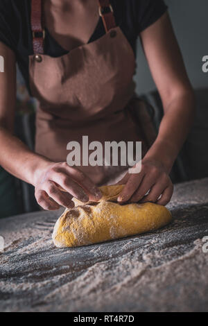 Woman Chef wearing apron kneading dough by hand at bakery Stock Photo