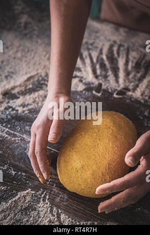 Woman Chef wearing apron kneading dough by hand at bakery Stock Photo