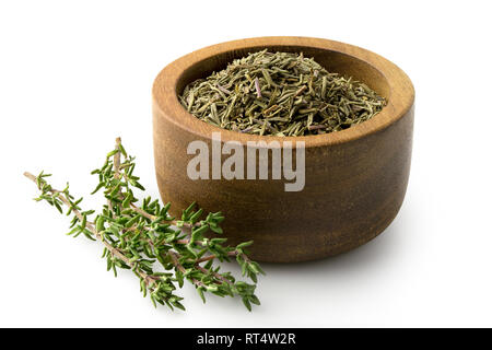 Dried rubbed thyme in a dark wood bowl next to fresh thyme sprig isolated on white. Stock Photo