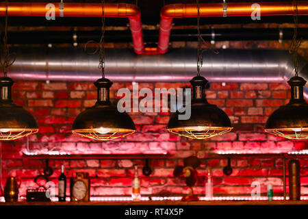 Steampunk style design element unusual lamps hanging in a row view over red brick wall inside cafe or restaurant Stock Photo