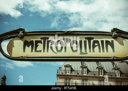 Art nouveau metropolitain sign in Paris, France ith traditional French real estate apartment building in the background  Stock Photo