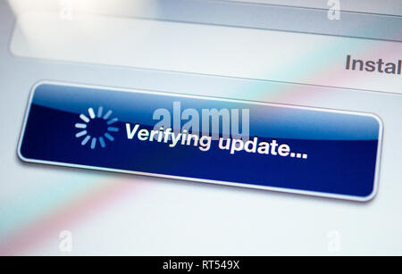 Verifying update message with spinning cursor on a modern tablet screen - tilt shift lens used Stock Photo