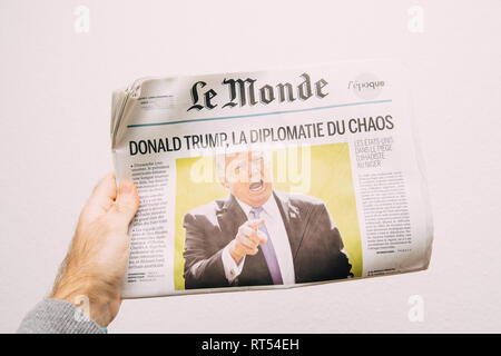 PARIS, FRANCE - NOV 6, 2017: Male hand holding against white background latest Le Monde newspaper featuring headline Donald Trump is Chaos Diplomacy Stock Photo