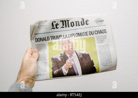 PARIS, FRANCE - NOV 6, 2017: Male hand holding against white background latest Le Monde newspaper featuring headline Donald Trump is Chaos Diplomacy Stock Photo