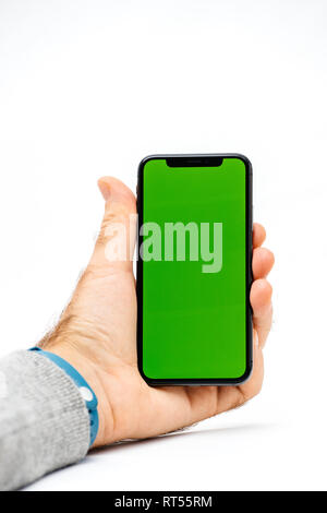 PARIS, FRANCE - NOV 5, 2017: New Apple iPhone X 10 smartphone with green chroma key backdrop against white background in male hand Stock Photo