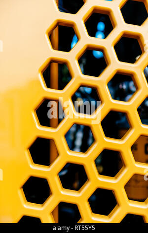 Metallic grill tractor part painted in yellow with multiple hexagonal shapes for ventilation and hot air exhaust Stock Photo